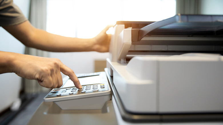 Person pressing buttons on a photocopy machine