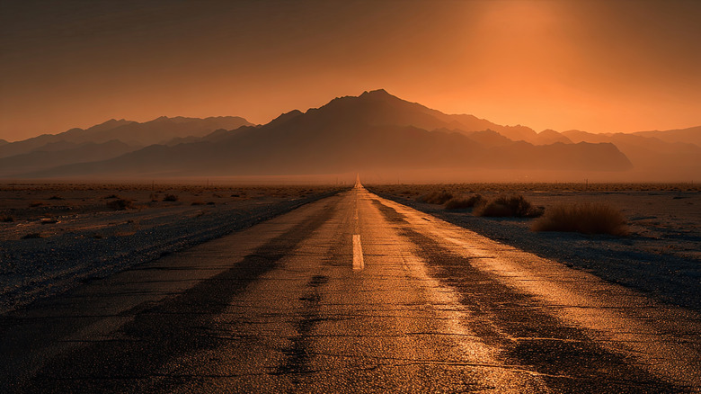 orange sky with mountains in the back with a road leading up to it