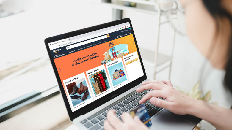 The Amazon website is displayed on a laptop as a woman shops, credit card in hand.