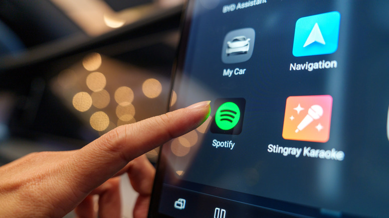 Spotify app icon on Android Auto screen with finger hovering above