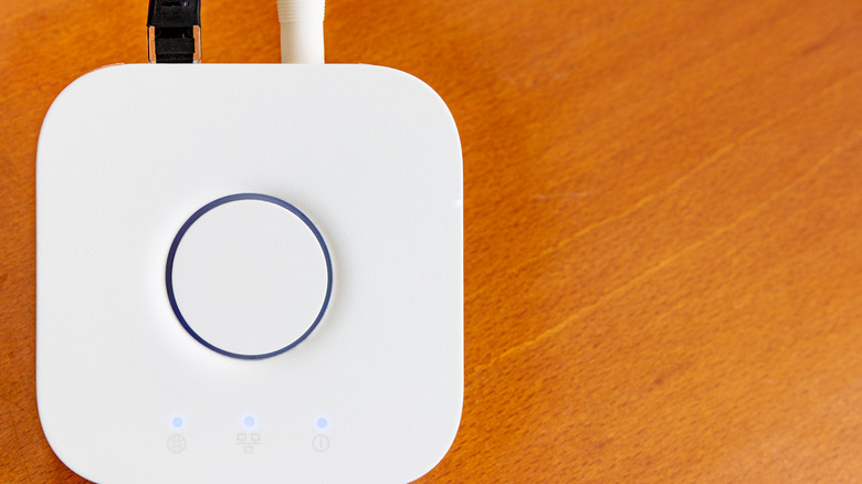 smart home hub resting on a wooden floor or table, cables visible from the back