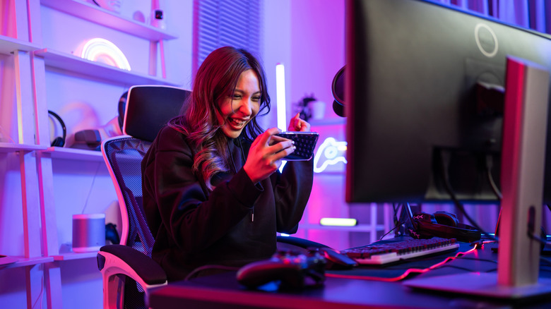 Person playing a mobile game at a neon-lit gaming desk.