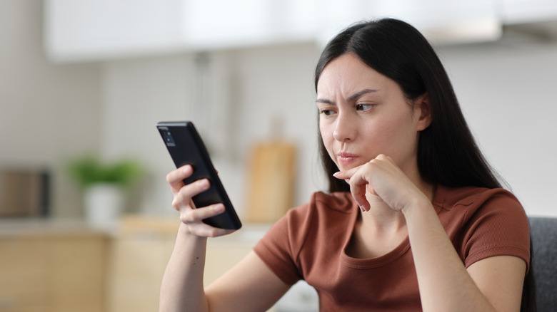 a confused woman looking at her phone