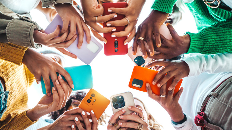 multiple people in a circle with their phones in their hands.