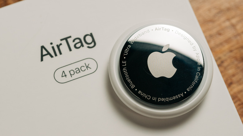 An Apple AirTag placed on top of an AirTag 4-Pack box.