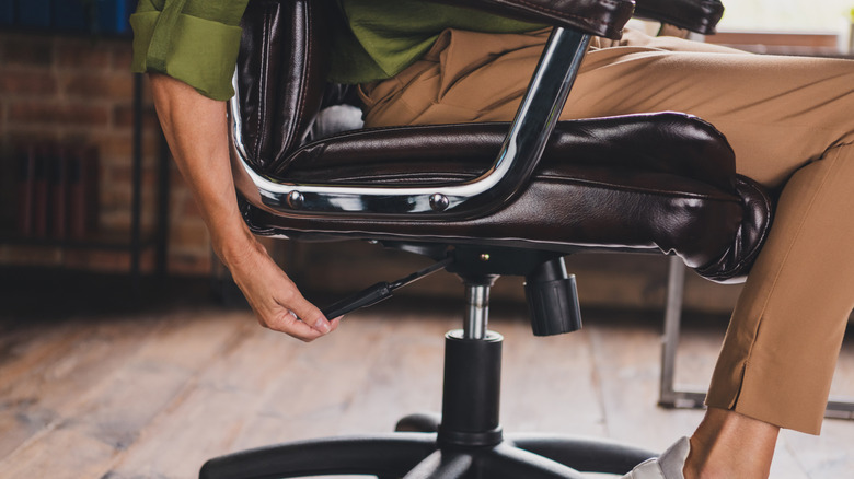 Person sitting in desk chair adjusts its height.