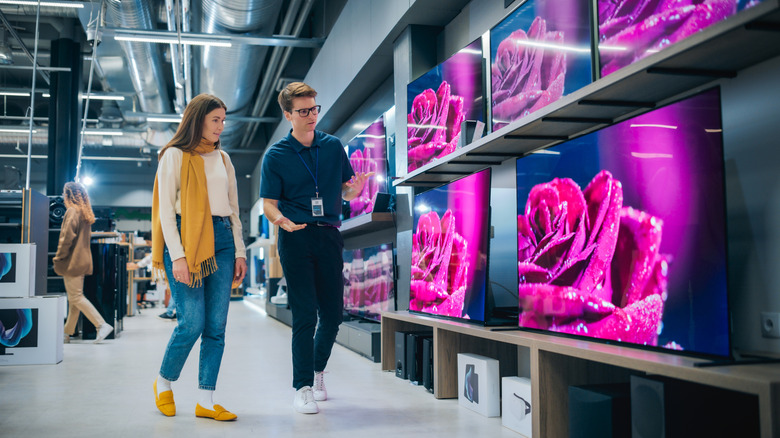A woman is shopping for a TV, a sales associate is guiding her.
