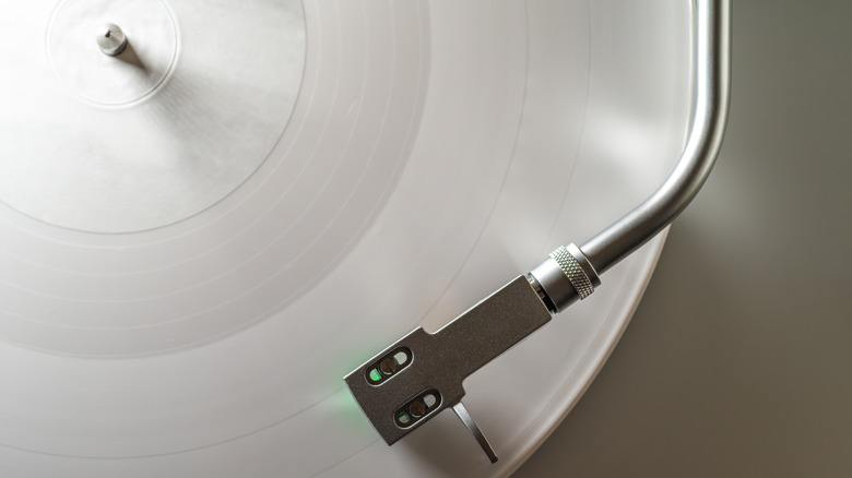 Overhead view of a turntable tonearm on a white vinyl record