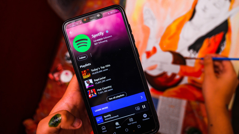 Hand holding a smartphone playing music on Spotify