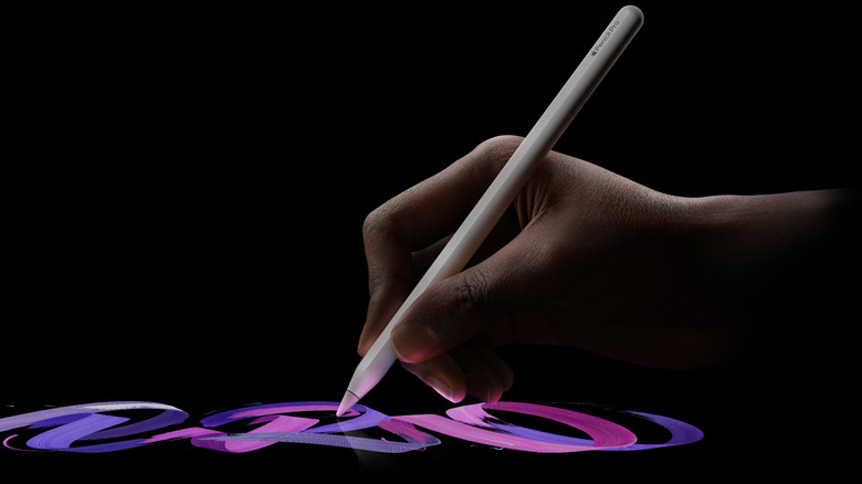 Close up of a hand writing with an Apple Pencil on a black background