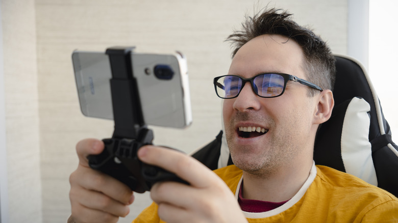 A man playing games on a phone using a mobile controller