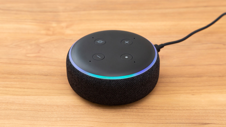 Amazon Echo smart speaker with a blue light ring on a wooden table.