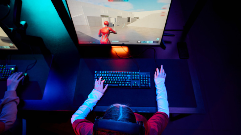 Person sitting at single-monitor computer playing a game
