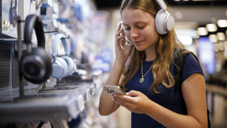 A woman testing headphones at an electronics store