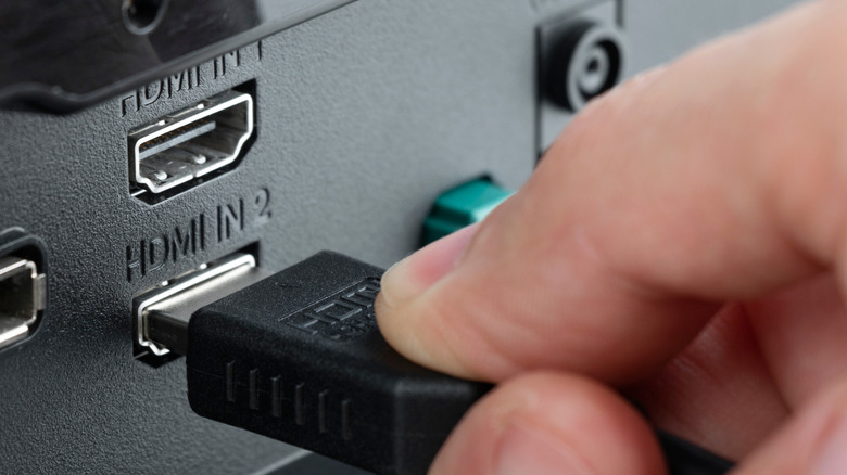 A hand inserting HDMI cable into a HDMI port