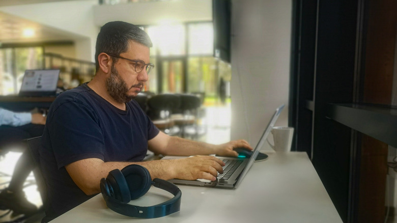 Man wearing glasses using a laptop