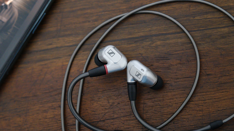 A pair of wired Sennheiser earbuds on a table near a cell phone