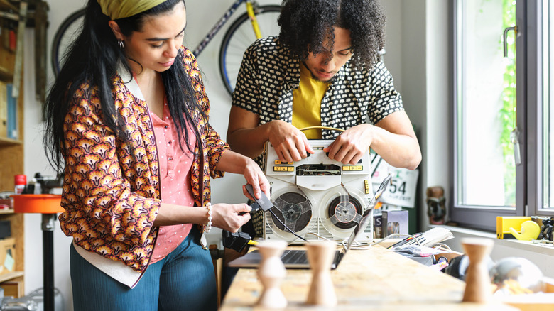 Two people inspecting pieces of older and retro tech