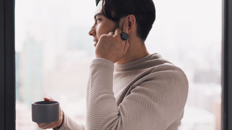 A person wearing a smart ring and holding a finger to an ear