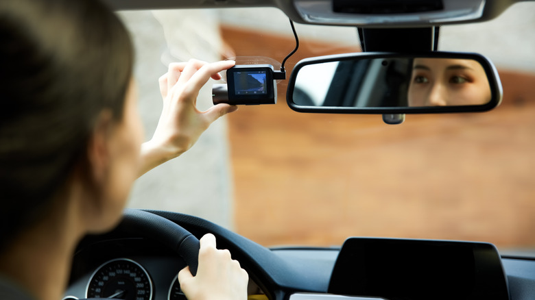 A person adjusting a dashcam in a car