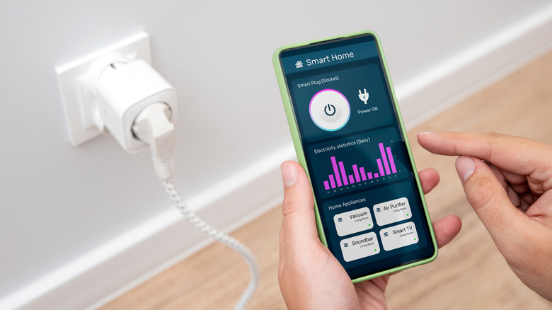 A person monitoring a smart home app with smart plug toggle on the screen