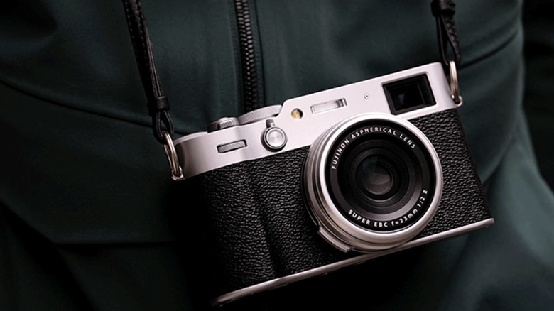 The Fujifilm X100VI seen slung around a photographer's neck.