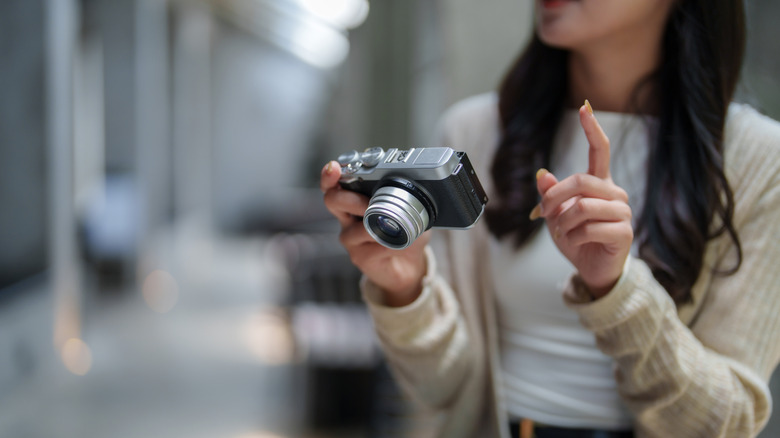 A photographer holding a compact digital camera while explaining