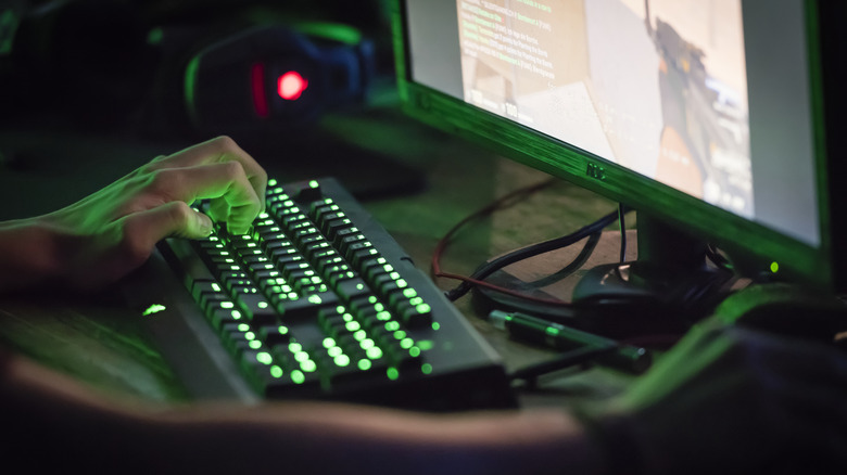 Close-up of person using a keyboard and mouse to play a video game on a computer