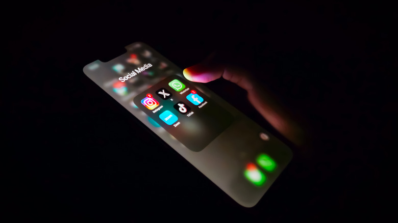 Close-up of hand using phone in dark, private setting