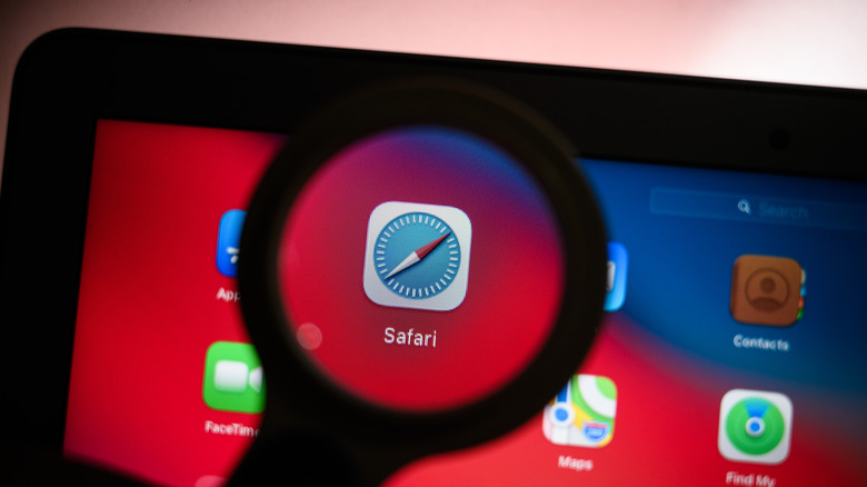 Safari icon shown through magnifying glass on an Apple MacBook
