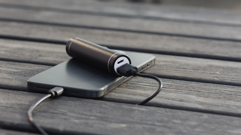 A battery pack charging a phone on a wooden surface