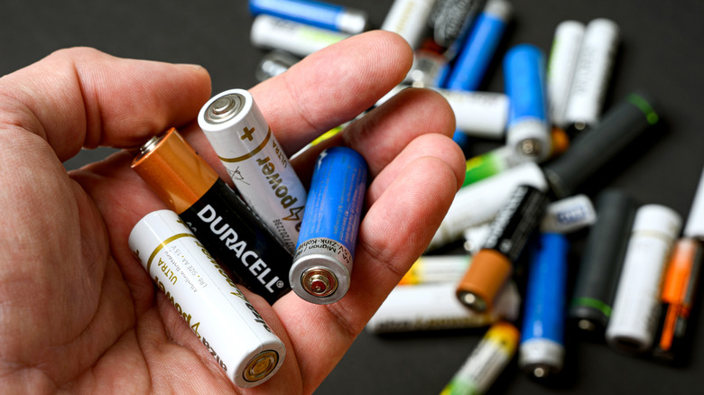 a hand holding different batteries