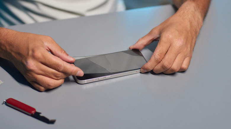 Person using tools to properly apply phone screen protector