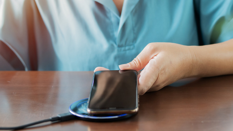 Close up of someone placing a smartphone on a wireless charging pad