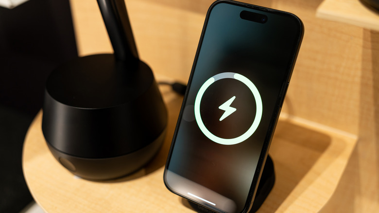A smartphone charging on a wireless charging stand
