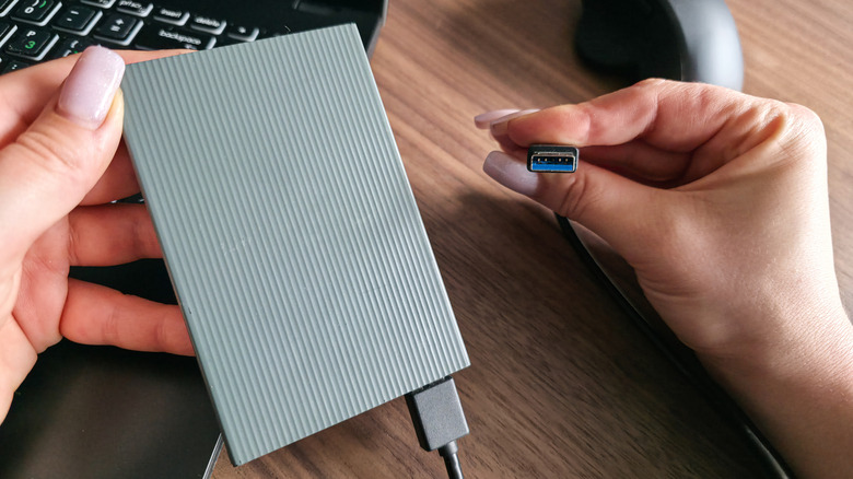 A person plugging an external hard drive to a laptop