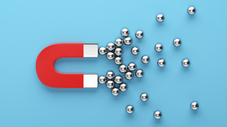 Metal spheres gravitated towards a red magnet on blue background