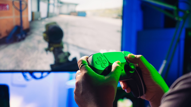 A person playing a PS5 game on a wall-mounted TV.
