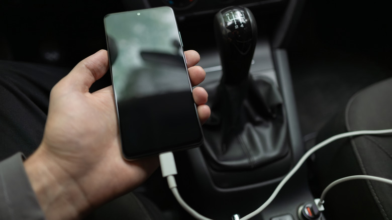 A person plugging in a phone in a car