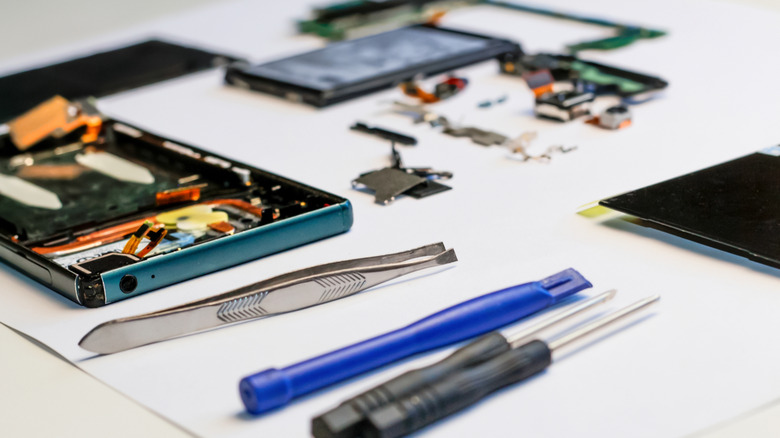 A smartphone next to some repair tools