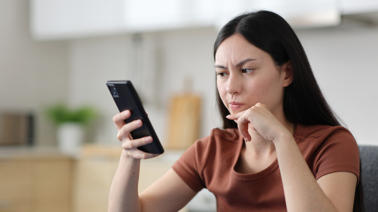 A person looking at a phone screen with annoyance