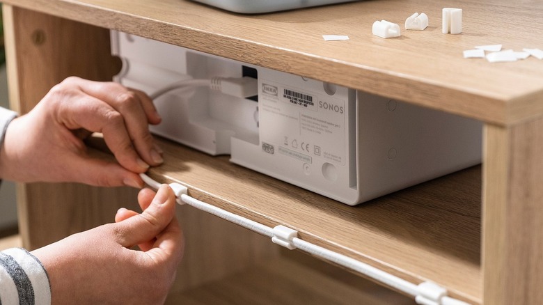 A person using Trixig cable management set to route an HDMI cable