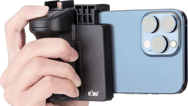 A hand holding a Kiwifotos Phone Camera Grip that's gripping a smartphone