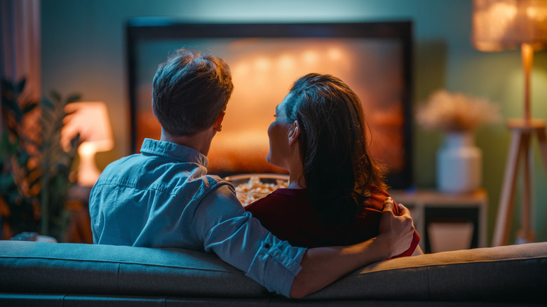 A couple siting on a couch and watching TV
