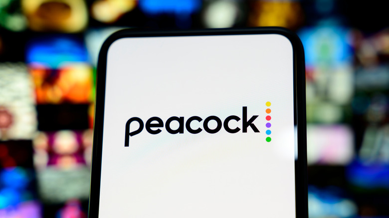 The Peacock logo on a smartphone with an illustration from a streaming site catalog in the background.