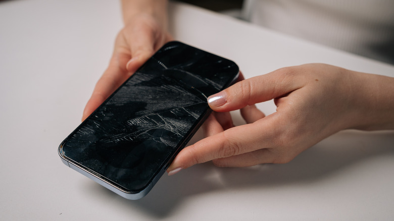 A person holding a cracked phone screen