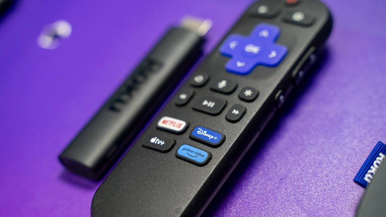 Roku remote control with streaming service buttons on purple background