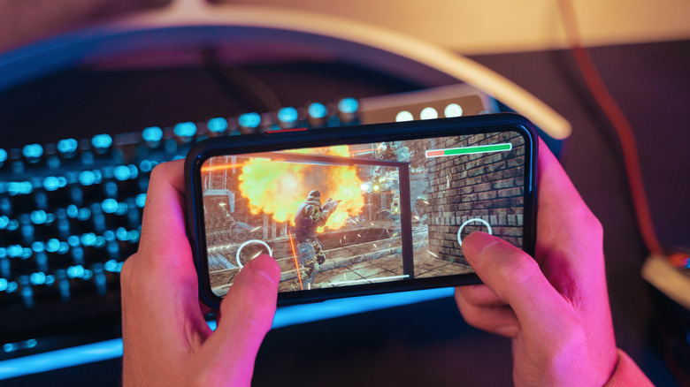 Close up of a gamer's hands playing a video game on a smartphone