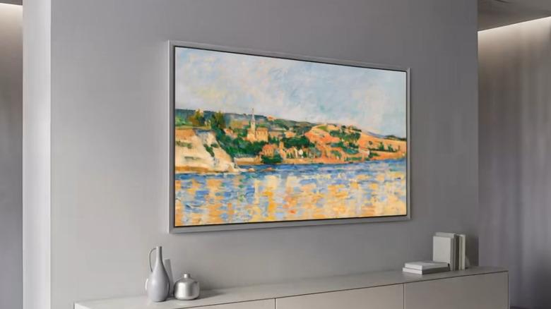 A thin OLED TV displaying artwork on the wall