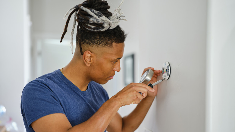 A person installing a thermostat